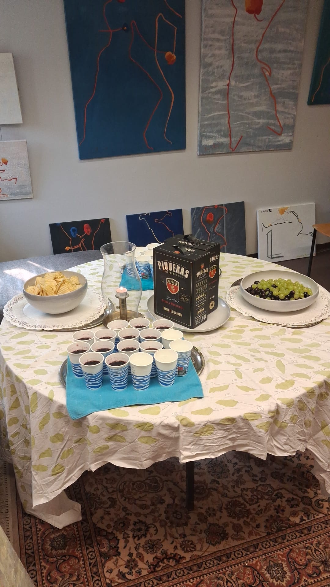 Näyttelyn avajaispöytä ja maalauksia seinillä